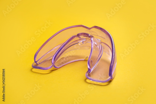 Dental mouth guard on yellow background, closeup. Bite correction