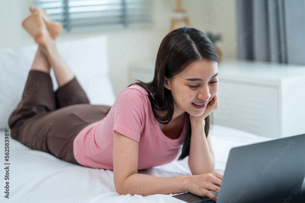 Asian attractive woman using laptop chat on bed at home in the morning. 