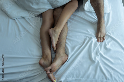 Close up feet of young couple starting foreplay and making love on bed. 