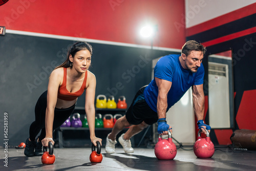 Two young athlete male and female exercising together in fitness gym. 