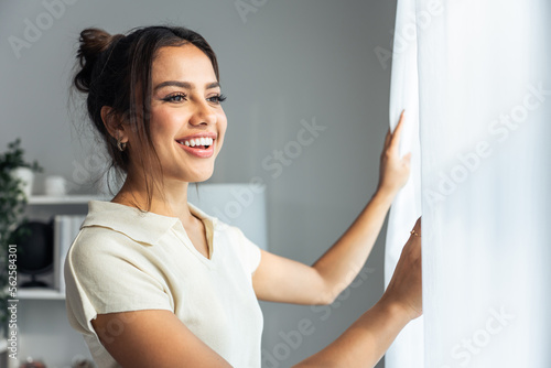 Asian beautiful woman approaches a window and open curtains in morning