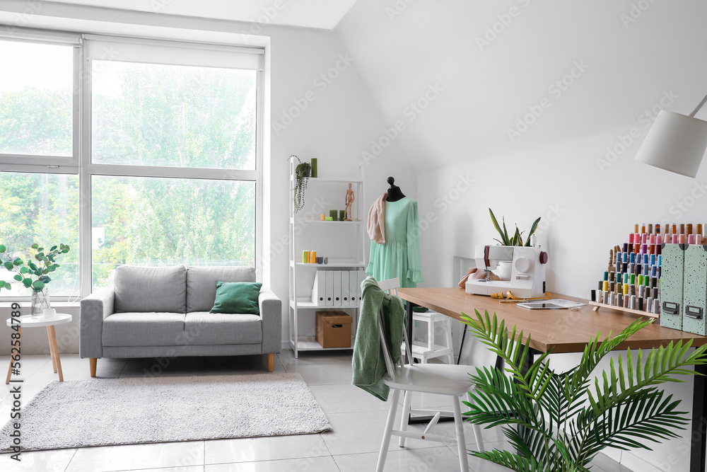 Fototapeta premium Interior of light atelier with tailor's workplace, mannequin and sofa
