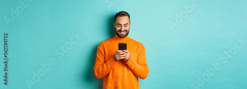Canvas Print Handsome man smiling and texting message on mobile phone, communicating online,