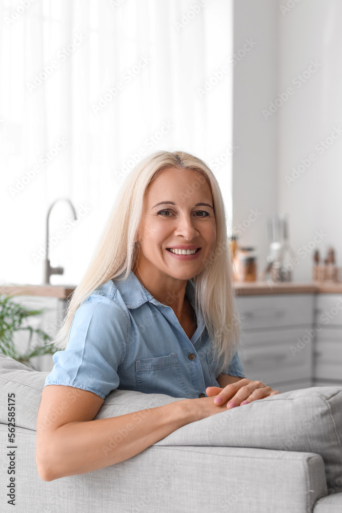 Mature woman sitting on sofa in kitchen Mature woman sitting on sofa in kitchen