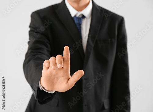 Young businessman using virtual screen on light background, closeup