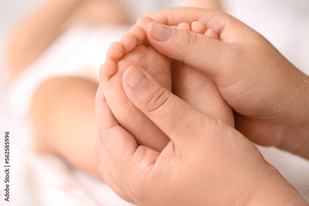 Mother massaging her baby's feet in bedroom, closeup Mother massaging her baby's feet in bedroom, closeup