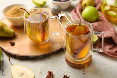 Board with glasses of fruit tea with cinnamon and pear on light background, closeup