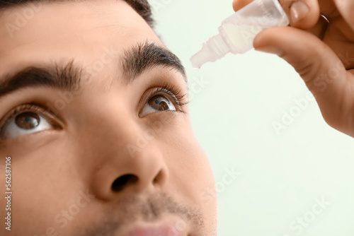 Young man using eye drops o...
