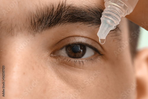 Young man with eye drops on...