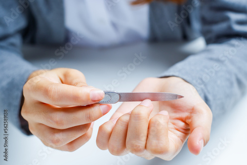 Woman filing nails to remove sharpness and trim nail edges. © Kt Stock