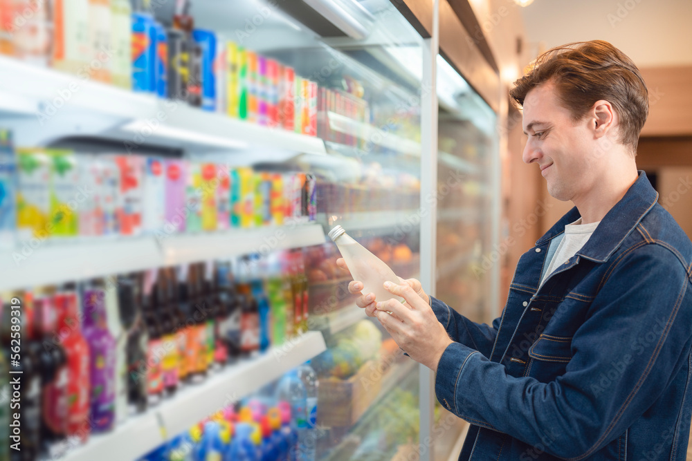 An European man but a bottle of mineral water from refrigerator cold in onvenience store