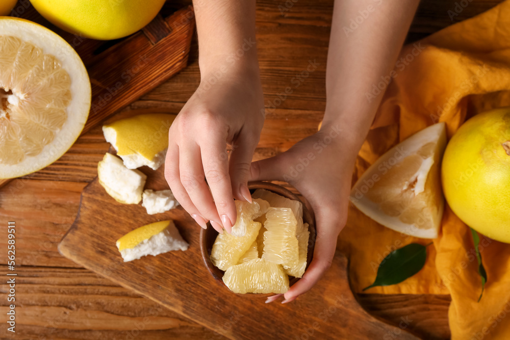 Female hands with pieces of fresh pomelo fruit on wooden background Female hands with pieces of fresh pomelo fruit on wooden background