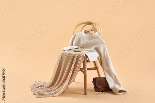 Chair with stylish clothes  book and bag on beige background