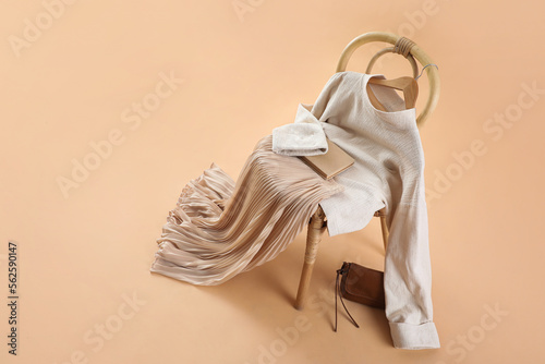 Chair with stylish clothes, book and bag on beige background