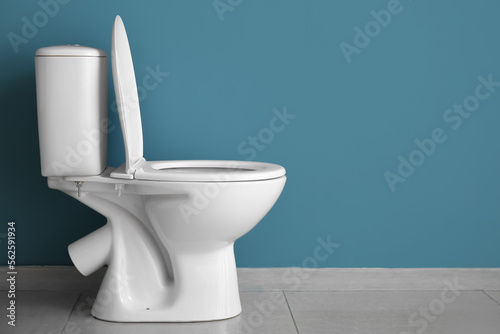 Ceramic toilet bowl near blue wall