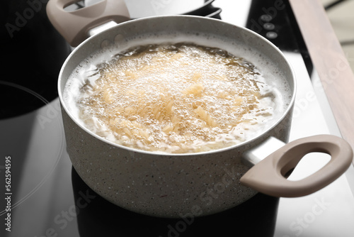 Cooking pot with boiling pasta on stove, closeup