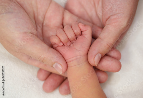 mother holding newborn baby hand on bed