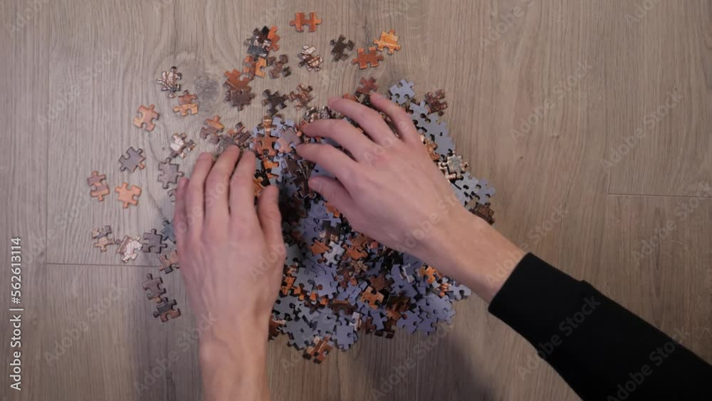 Hands flip puzzle pieces up, top down time lapse.
