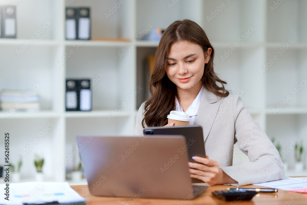 Young beautiful Asian businesswoman working with laptop computer and checking important documents in office, smiling and happy at work. Young beautiful Asian businesswoman working with laptop computer and checking important documents in office, smiling and happy at work.
