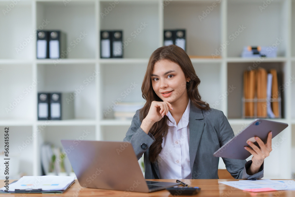 Young beautiful Asian businesswoman working with laptop computer and checking important documents in office, smiling and happy at work. Young beautiful Asian businesswoman working with laptop computer and checking important documents in office, smiling and happy at work.