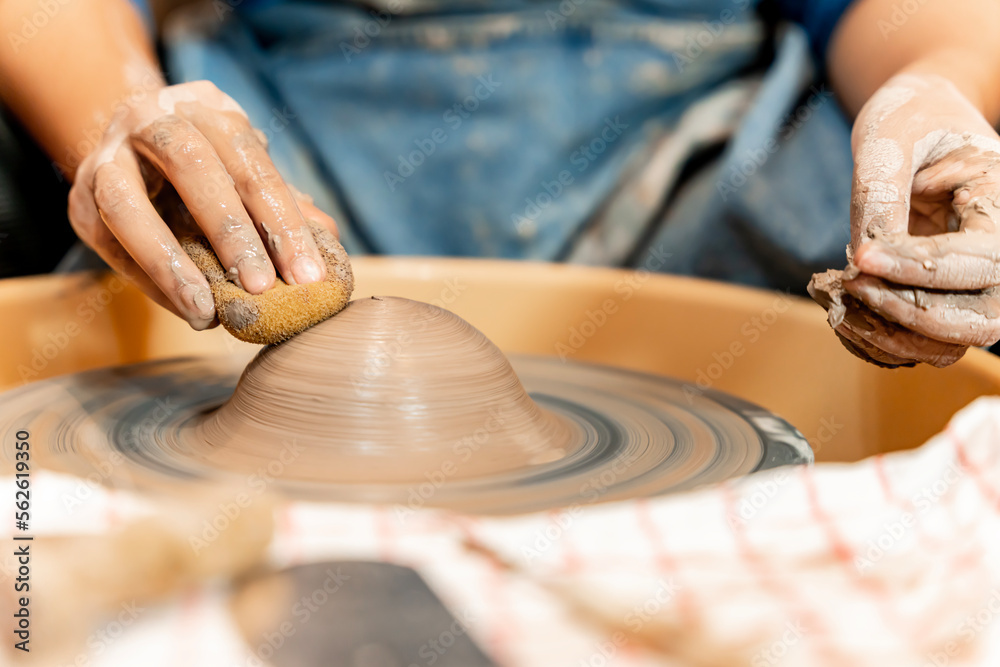 earthenware The art of sculpting clay with ceramics being molded by hand on a spinning machine. with the right posture to create a plate or vase professionally