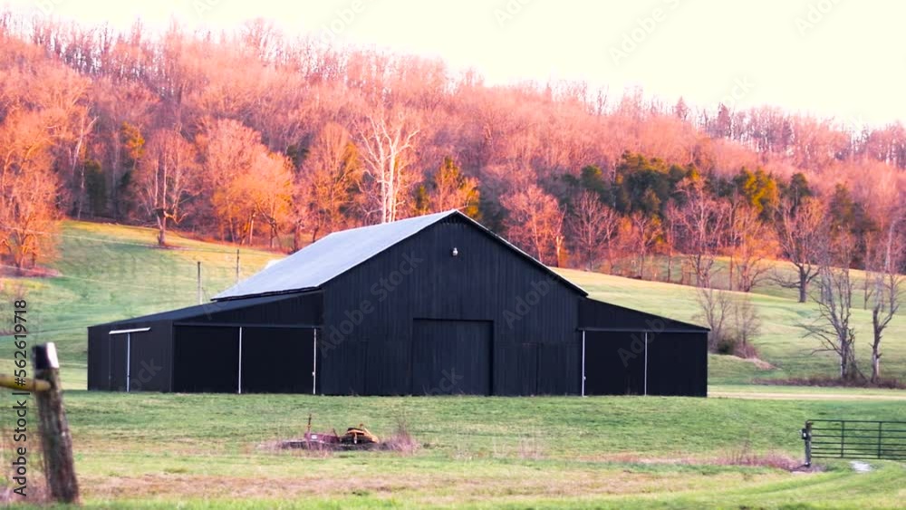 Still image of a black barn at the base of a hillside covered with fall foliage in Kentucky. Still image of a black barn at the base of a hillside covered with fall foliage in Kentucky.