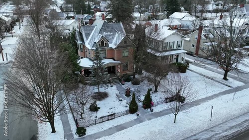 Slow, cinematic drone shot of victorian house during snow storm. Beautiful snow flurries fall on home decorated for Christmas. photo
