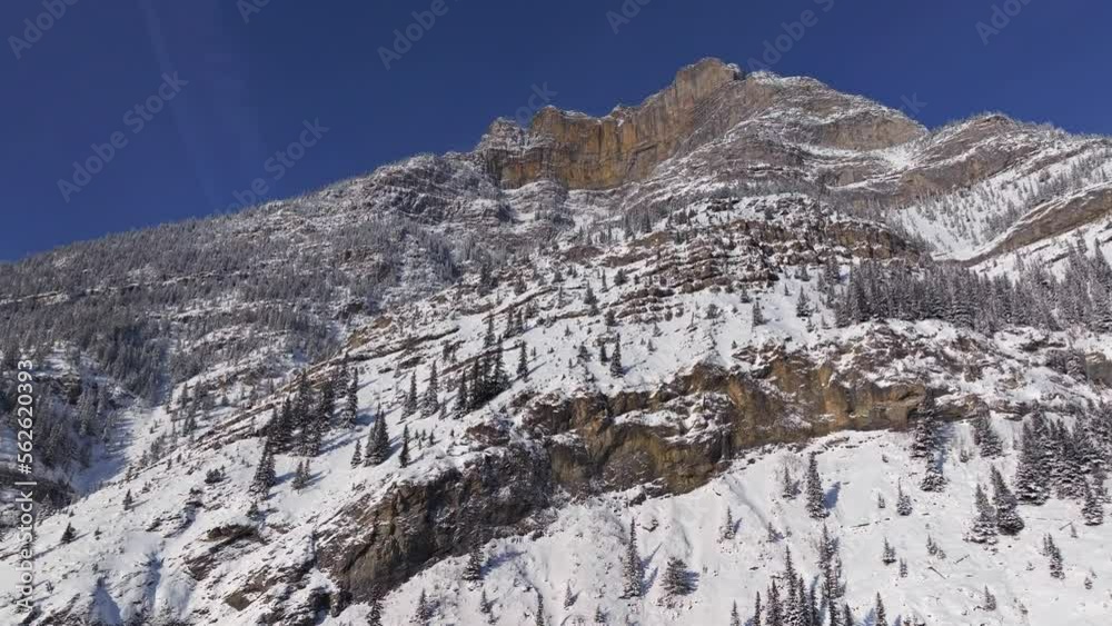 ascending drone shot of Grotto Mountain in Canmore Alberta Canada near Banff National Park during sunny winter day covered in snow ascending drone shot of Grotto Mountain in Canmore Alberta Canada near Banff National Park during sunny winter day covered in snow