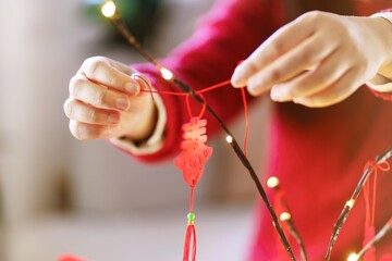 Asian Woman decorated house for Chinese New Year Celebrations. putting traditional pendant to the Chinese Lunar New Year for good luck. Chinese word means blessing