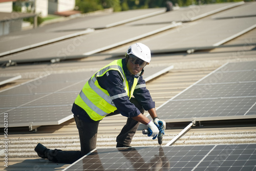 Well-equipped worker in protective clothing working and examining solar panels on a photovoltaic rooftop plant. Concept of maintenance and installation of solar station. © FotoArtist