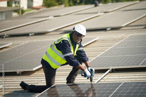 Well-equipped worker in protective clothing working and examining solar panels on a photovoltaic rooftop plant. Concept of maintenance and installation of solar station.