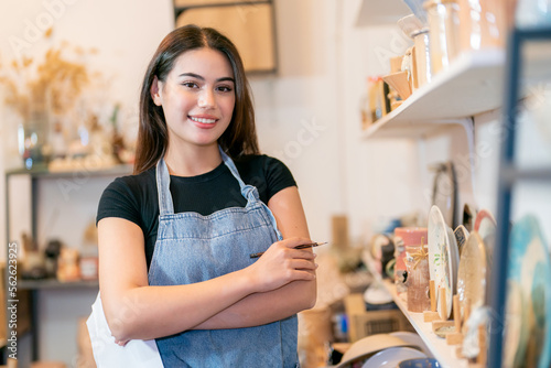 Portrait of female Pottery shop owner and ceramics manual worker in her small business.