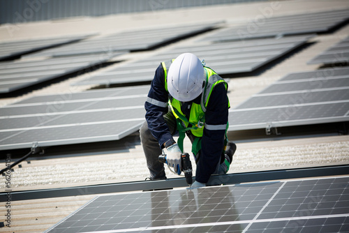 Bild auf Leinwand Well-equipped worker in protective clothing working and examining solar panels on a photovoltaic rooftop plant