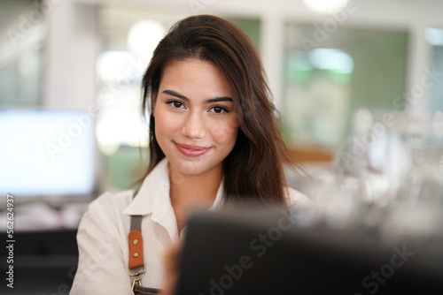 Portrait of Asian female Barista or coffee owner using coffee machine and looking to camera at bar counter in coffee shop cafe, Small business owner concept