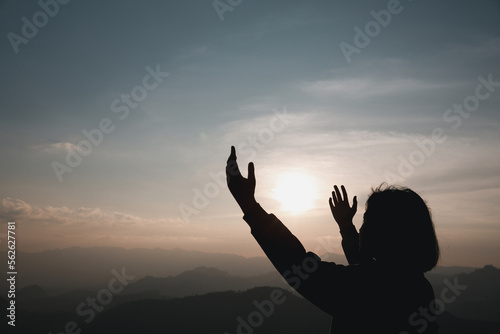 Faith christianity of christian worship concept. Spiritual prayer hands over sun shine with blurred beautiful sunset background. Woman praying to god with hopeful blessing against sunset.