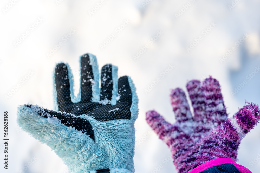 A pair of mismatched gloves on a child held over a white snow background A pair of mismatched gloves on a child held over a white snow background