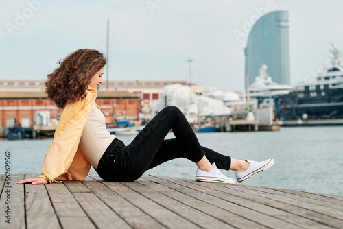 Young woman relaxing sitting outdoors near the water. © alvaro