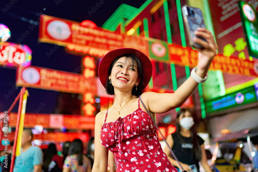 night photo of thai woman taking selfie at Yaowarat Chinatown in bangkok thailand during chinese new year celebrations
