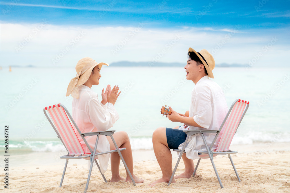 Asian traveller couple sitting and see sunset togather on the beach with longtail boat background