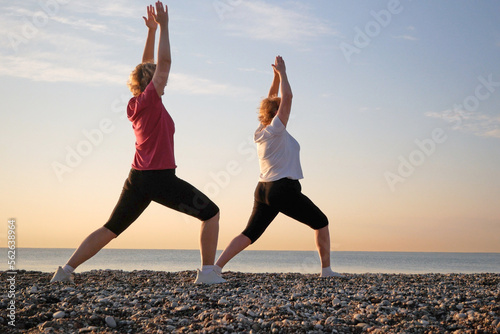 Wallpaper Mural Two women doing yoga performing asanas and enjoying life on the beach sea, sunset time Torontodigital.ca