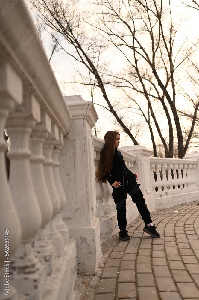 A girl with long hair is walking in the park. Beautiful warm sunset. A photo of a pretty young woman smiling at the wind in long curly brunette hair. A girl with long hair is walking in the park. Beautiful warm sunset. A photo of a pretty young woman smiling at the wind in long curly brunette hair.