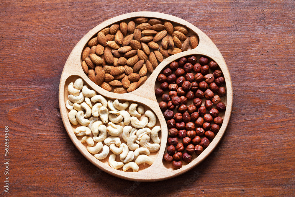 Top view of hazelnuts, cashews, and almonds on wooden background. Organic healthy food. Diet food with healthy dietary fiber and polyunsaturated fatty acids. Flat lay, close up, mockup