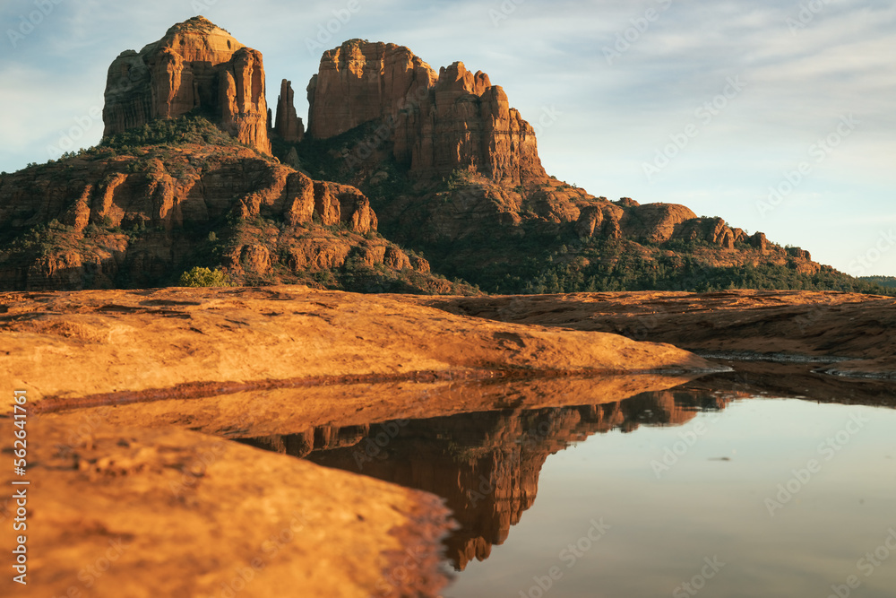 Red rock cathedral rock illuminated during sunset reflecting on small natural pool in the american southwest of Sedona Arizona after a heavy rain fall