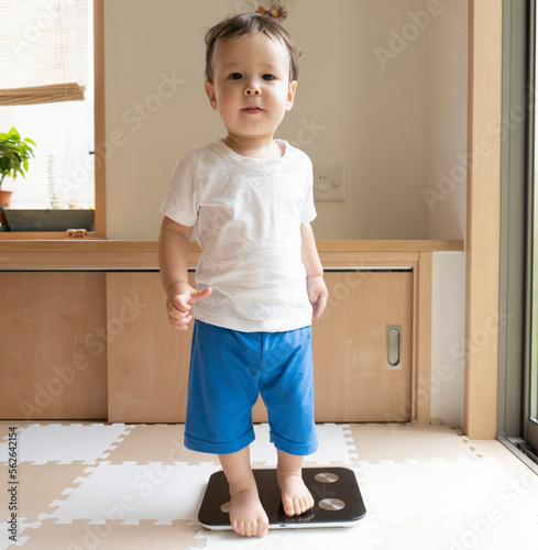 A boy gets on a weight scale photo