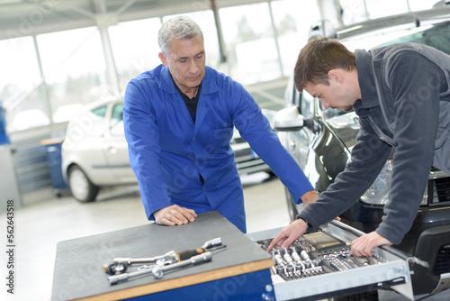 teacher and student choosing appropriate tools in mechanic school