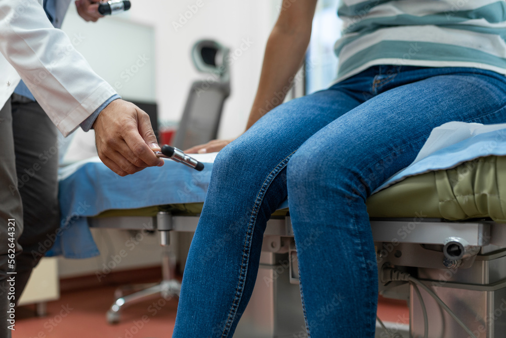 The neurologist testing knee reflex on a female patient using a hammer. Neurological physical examination. Selective focus, close up The neurologist testing knee reflex on a female patient using a hammer. Neurological physical examination. Selective focus, close up