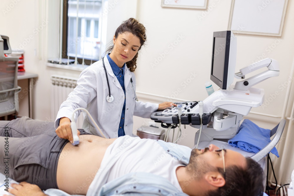 Ultrasound diagnosis of the stomach on the abdominal cavity of a man in the clinic, close-up view. The doctor runs an ultrasound sensor over the patient's male abdomen. Diagnostics of internal organs. Ultrasound diagnosis of the stomach on the abdominal cavity of a man in the clinic, close-up view. The doctor runs an ultrasound sensor over the patient's male abdomen. Diagnostics of internal organs.
