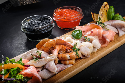 assorted fish and seafood on a wooden tray