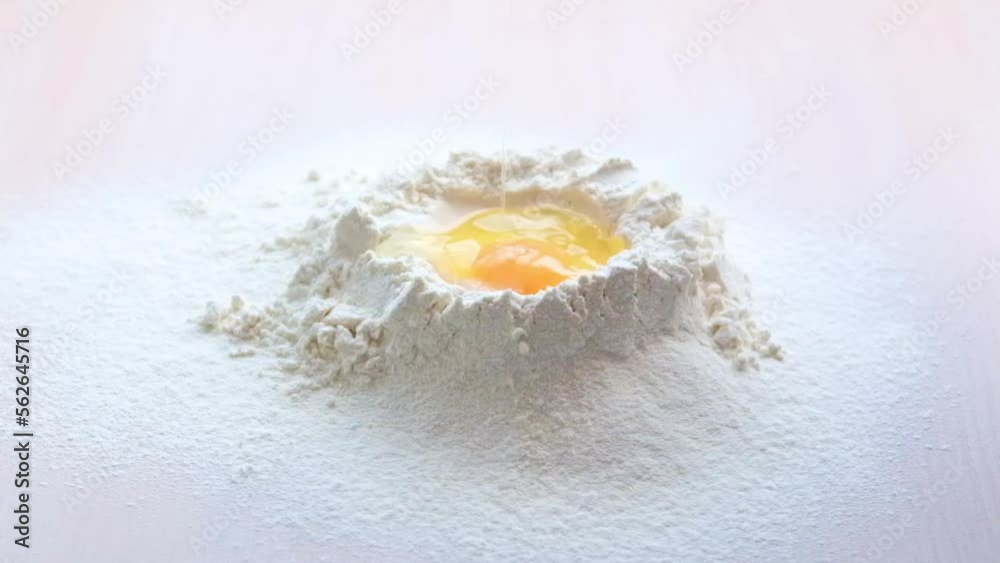 Slow motion of falling eggs into flour. Food footage. Egg dripping into flour, slow motion yolk falls into flour Food blog products Bakery products. Dough preparation flour volcano with broken egg Slow motion of falling eggs into flour. Food footage. Egg dripping into flour, slow motion yolk falls into flour Food blog products Bakery products. Dough preparation flour volcano with broken egg