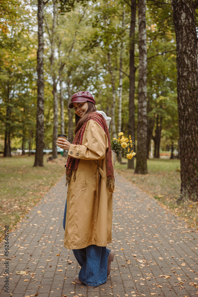 Side view full length of happy woman with cup of coffee standing in autumn park Side view full length of happy woman with cup of coffee standing in autumn park